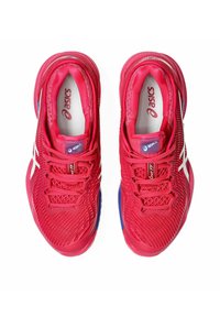 Baskets de sport rouges avec une tige en maille, dotées d'accents blancs, d'un col rembourré et d'une semelle texturée, conçues pour le confort et le soutien.