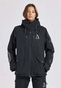 Giacca impermeabile nera con cappuccio, chiusura frontale con zip e tasche. Presenta il logo "SLADE", corde regolabili e una superficie testurizzata.