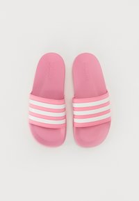 Roze klizne sandale s teksturiranom površinom, s tri bijele pruge preko gornjeg remena i utisnutim logotipom na unutrašnjem dijelu.