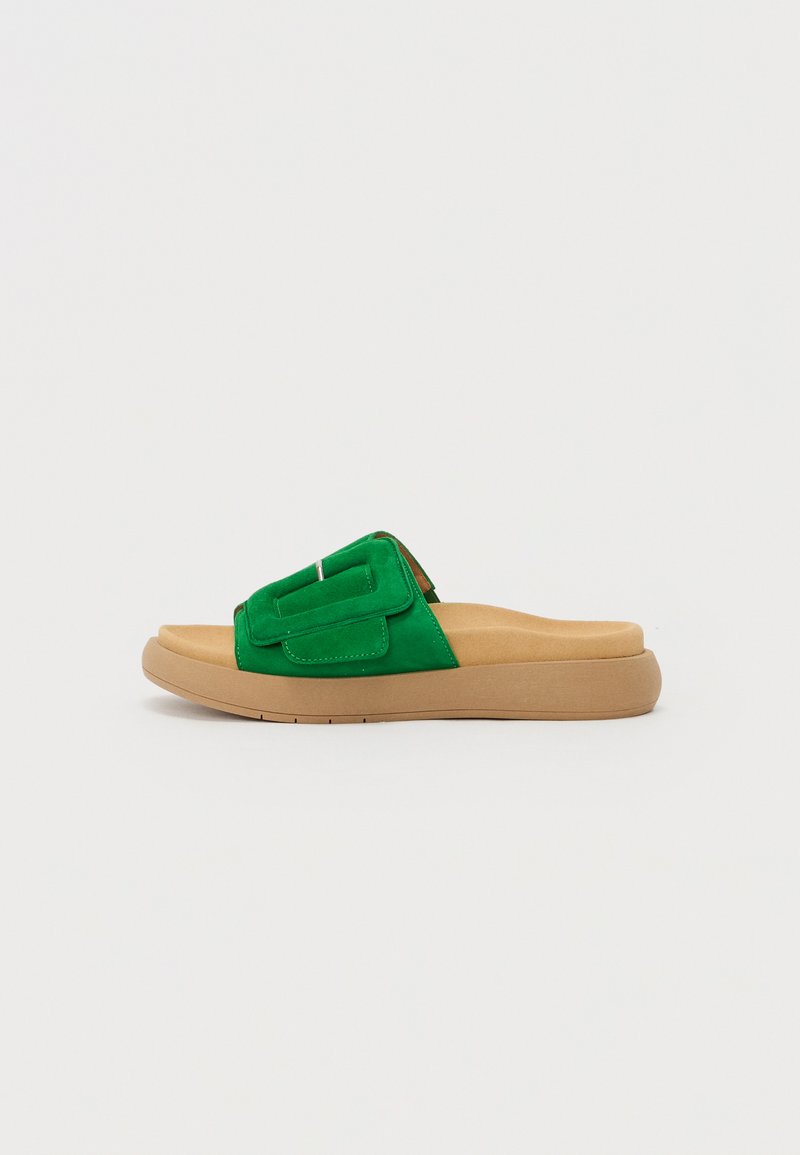 Sandal de camurça verde, tipo slip-on, com uma tira larga sofisticada, apresentando um detalhe costurado, acompanhada de uma sola acolchoada em tom beijinho claro.