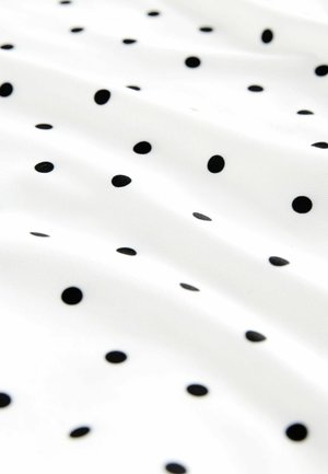 Balts audums ar melniem punktiņiem. Virsma ir gluda, ar atšķirīga izmēra punktiņiem, kas izkārtoti izkaisītā rakstā visā virsmā.