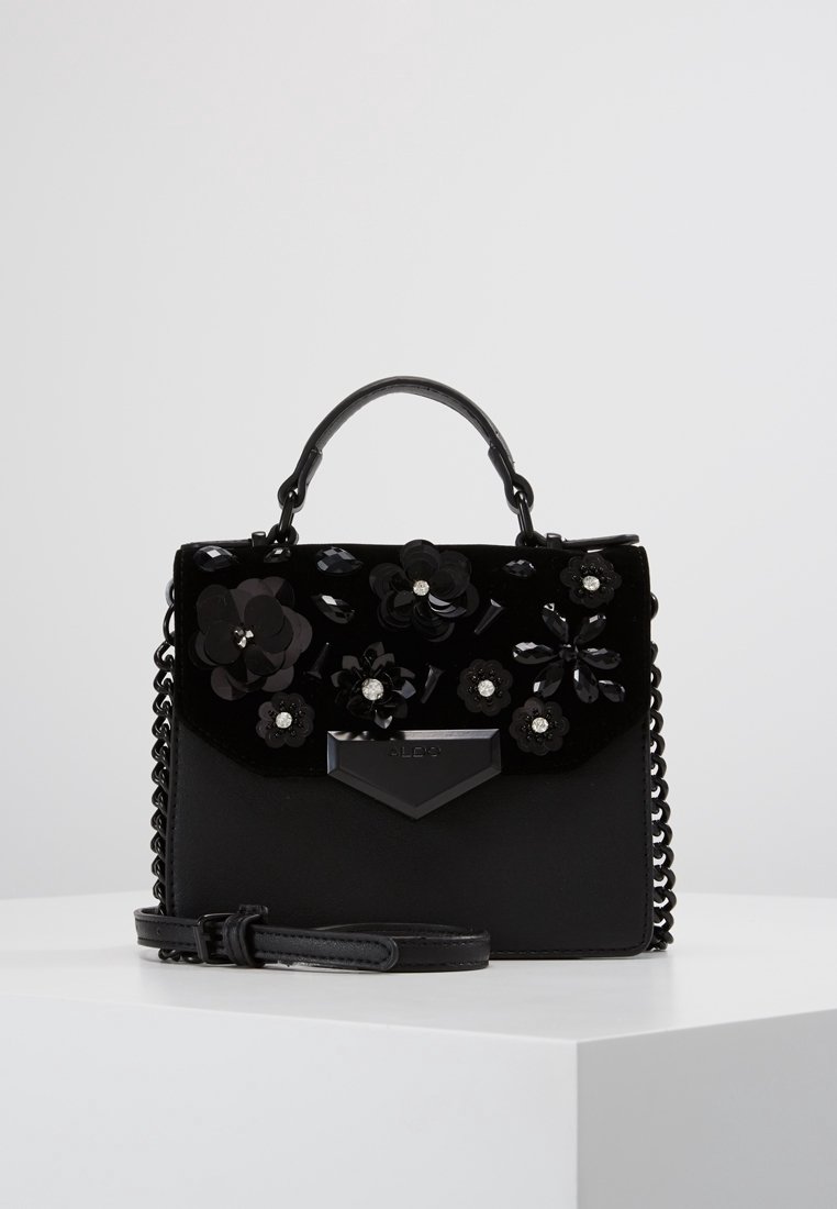 Czarna torebka z aksamitu z kwiatowymi zdobieniami, łańcuszkową rączką i skórzanymi akcentami. Charakteryzuje się usztywnionym kształtem i odpinanym paskiem.