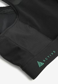 Čierny športový top s priedušnou sieťovinou, s textúrovaným spodným pásom a zeleným akcentom loga "ACTIVE".