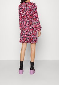 Květinové šaty v růžové a černé barvě, dlouhé rukávy, elastický pas, ke kolenům. V kombinaci s černými kotníkovými botami a fialovými blokovými podpatky.