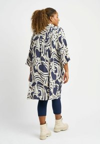 Long, loose wrap coat featuring a blue and cream abstract pattern, made of textured fabric, with three-quarter sleeves and a collar.
