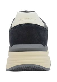 Vista posteriore di una sneaker con suede nero, toppa in pelle bianca sul tallone e una suola spessa beige con battistrada grigio.