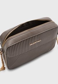 Borsa a tracolla in pelle grigia con design a righe trapuntato, hardware in tonalità oro, logo "VALENTINO" prominente e chiusura con doppia cerniera.