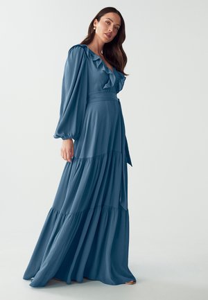 Long blue dress featuring ruffled neckline, billowy sleeves, and tiered skirt with a textured fabric. Includes a tie at the waist.