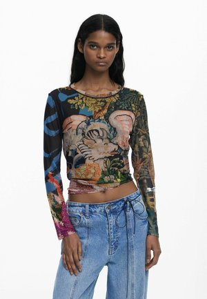 Long-sleeve, fitted top with a multicolored floral and animal print, made of sheer fabric. Paired with high-waisted denim jeans.