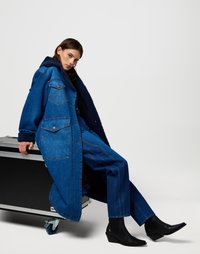Lange blauwe denim jas met een marineblauwe fleece kraag, gecombineerd met blauwe rechte denim broeken en zwarte wedge enkellaarzen.
