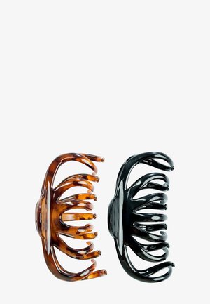 Deux pinces à cheveux en plastique, l'une en écaille de tortue marron et l'autre en noir uni, présentées côte à côte sur un fond blanc.