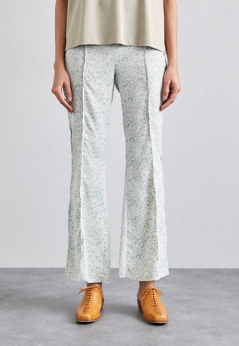 Lichtgewicht broek met bloemenpatroon in zacht mintgroen, met zijslitsen, vergezeld van tan kleurige veterschoenen voor een contrasterende uitstraling.