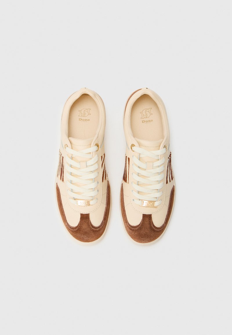 Baskets beiges avec des accents en daim marron, lacets blancs et détail de logo doré. Dispose d'un design bas et de bandes latérales texturées.