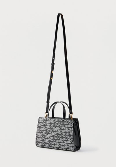 Sac à main noir et gris avec motif répétitif du logo DKNY, deux poignées courtes et une longue bandoulière réglable avec garnitures dorées.