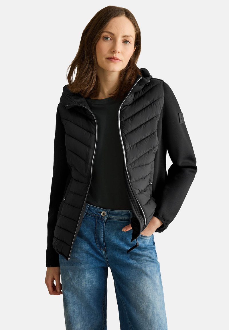 Giubbotto piumino nero con cappuccio, caratterizzato da un design trapuntato. Maniche lunghe in tessuto liscio e tasche laterali. Da abbinare a jeans in denim.