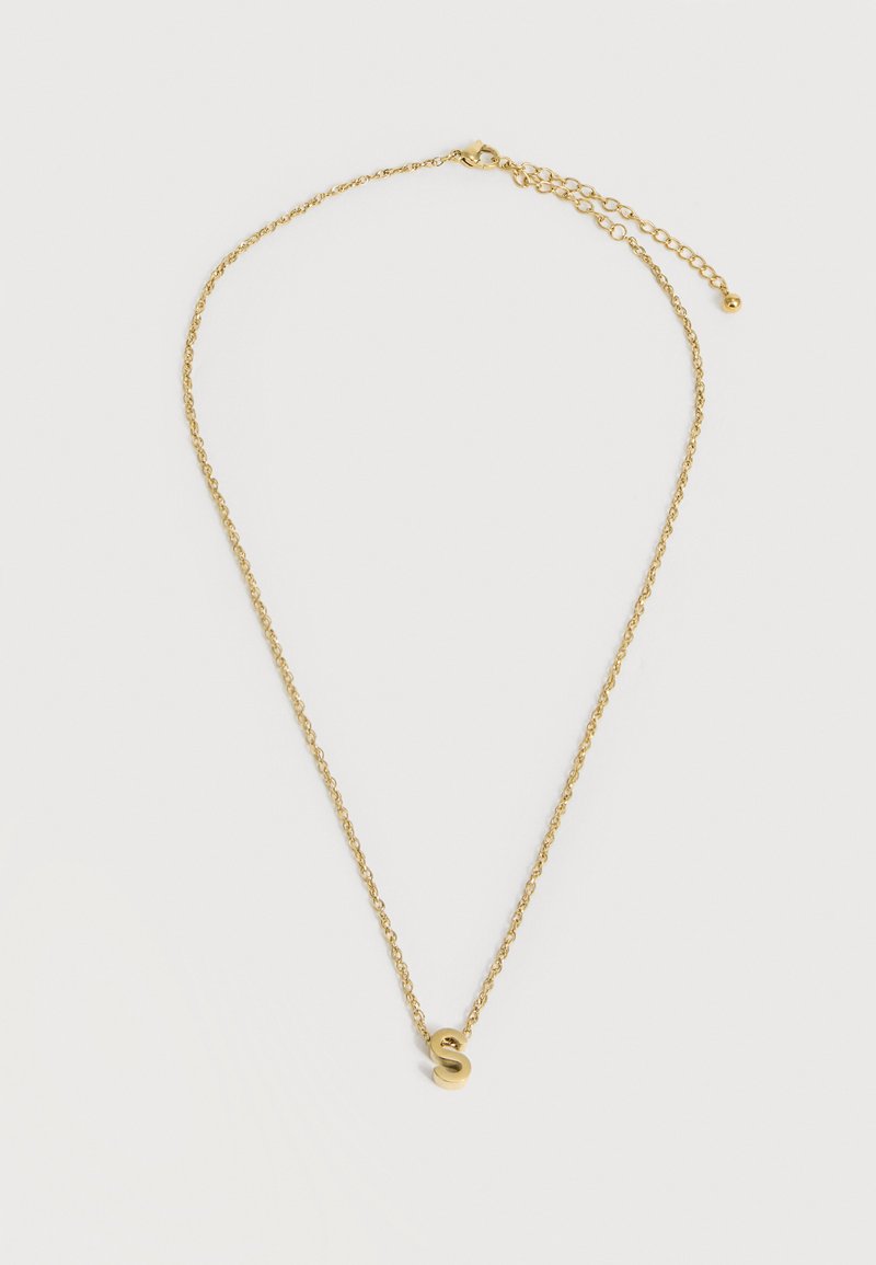 Collier délicat en chaîne d’or avec fermoir ajustable et petit pendentif en or en forme de lettre « S » centré sur fond blanc.