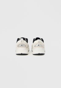 Λευκά και μαύρα αθλητικά παπούτσια με μαλακή σόλα, λείο δέρμα και υφασμάτινο υλικό, με ανακλαστικό ασημί λογότυπο στη φτέρνα.