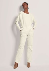 Crème-kleurig geribbeld sweater en bijpassende broek van een textuurstof, met lange mouwen, een ontspannen pasvorm en rechte pijpen.