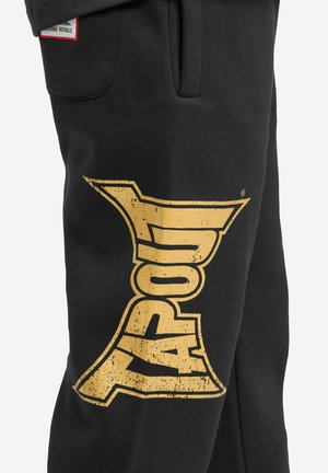 Black sweatpants made of soft material feature a large, distressed gold graphic of the word "XAPOUL" on the left leg.