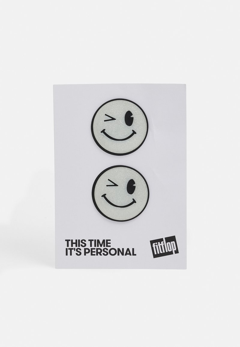 Dois patches de rostos sorridentes com contornos pretos em um cartão branco. Um pisca o olho; ambos têm uma textura brilhante. O texto diz "DESSA VEZ É PESSOAL."