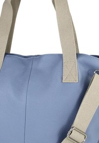 Blauwe leren totebag met een gestructureerd oppervlak. Voorzien van beige stoffen handvatten en een verstelbare band met metalen details voor veelzijdigheid.
