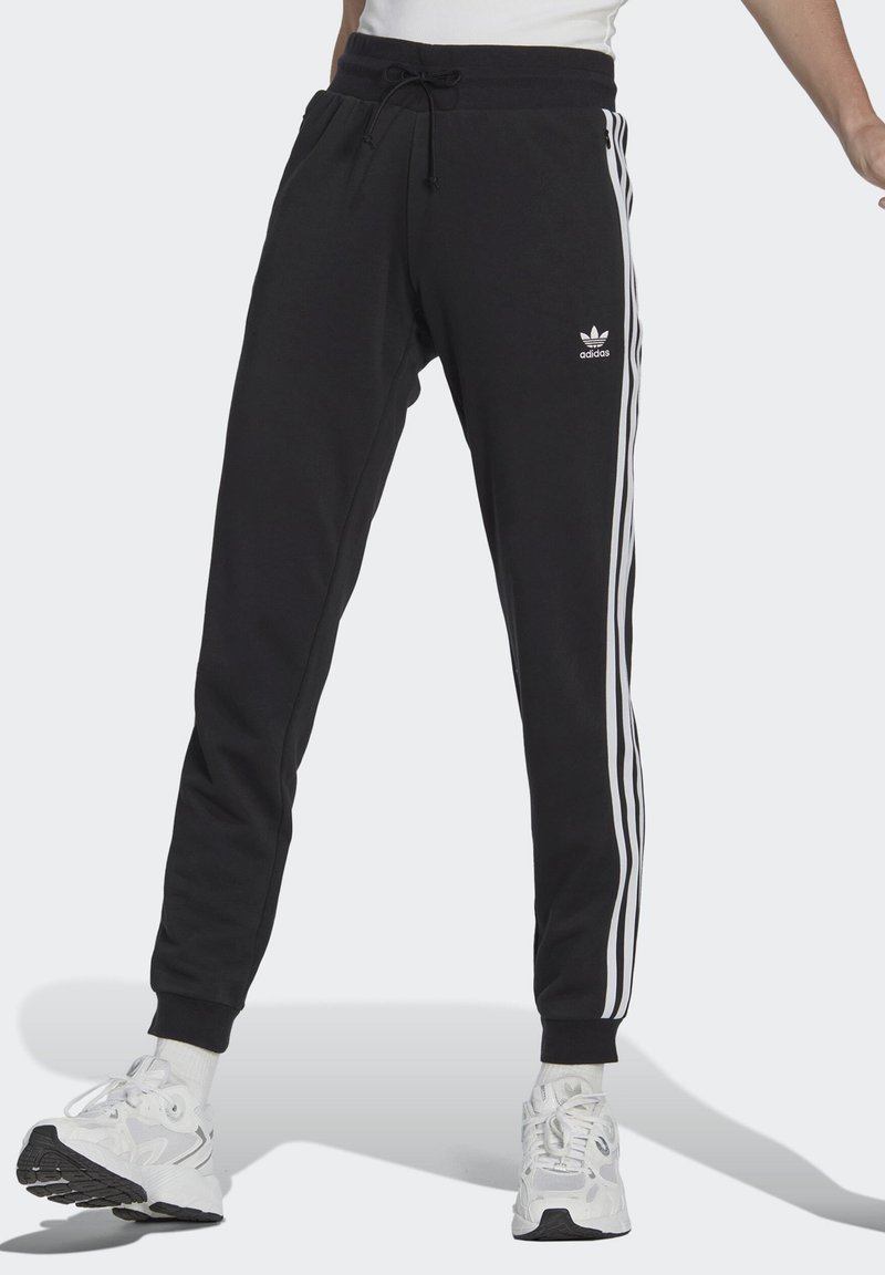 Pantaloni sportivi neri con strisce bianche sui lati, vita con coulisse e polsini a costine. Presenta un logo adidas sulla coscia sinistra.