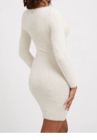 Robe blanche moulante réalisée en matériau doux et pelucheux. Manches longues et encolure arrondie, avec un ourlet côtelé. Design simple.