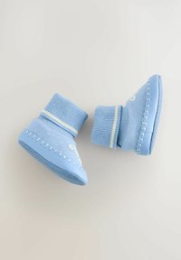 Šviesiai mėlyni kūdikių batukai su raukšlėta apykakle, minkšta tekstūra ir dekoratyvinėmis siūlėmis palei padą. Yra geltonų dryžuotų akcentų.