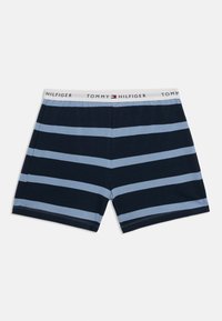 Μπλε ναυτικό βαμβακερό μποξεράκι με ανοιχτό μπλε οριζόντιες ρίγες. Η ελαστική μέση έχει το λογότυπο "TOMMY HILFIGER" σε λευκό.