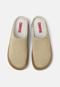 Béžové slip-on boty s hladkým nubukovým svrškem, bílou vnitřní podšívkou a červeným logem "CAMPER". Gumová podrážka s texturovaným gripem.