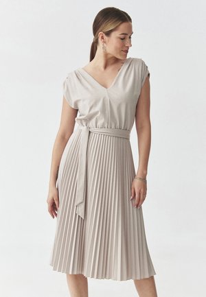 Pleated dress in light beige with a v-neckline, cap sleeves, and a matching belt at the waist. The fabric appears soft with a subtle sheen.