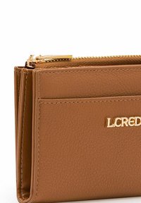 Braune Lederbörse mit texturierter Oberfläche, ausgestattet mit einem goldfarbenen Reißverschluss und dem geprägten "LCRED"-Logo auf der Vorderseite.