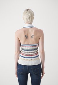 Top halter tricotado com riscas horizontais multicoloridas, apresentando uma textura canelada. As costas exibem duas tatuagens de borboleta acima de uma gola branca.