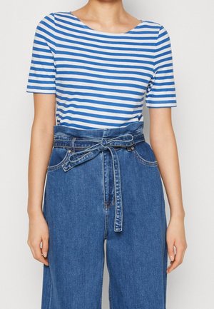 Blå- og hvidstribet kortærmet top kombineret med blå denimbukser i høj talje, udstyret med et bindebånd og vide ben.