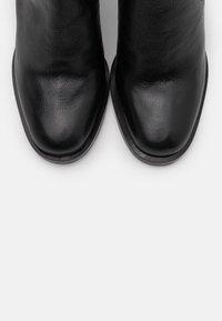 Botines negros de cuero con textura suave, puntera cuadrada y tacón bajo. Presentan un diseño minimalista sin acentos decorativos.