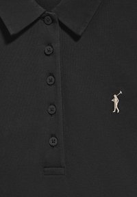 Camisa polo negra con una superficie de punto texturizada, que presenta seis botones negros y una pequeña figura bordada en color claro sosteniendo un palo de golf.