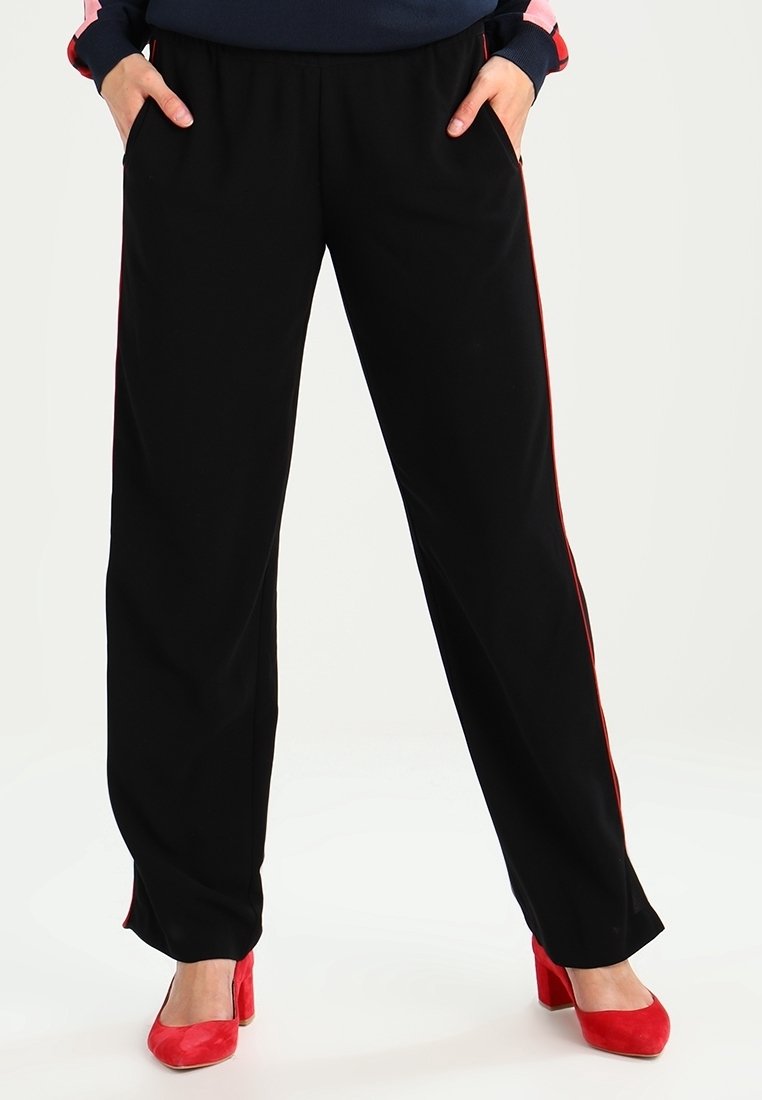 Czarne spodnie w luźnym kroju, z bocznymi paskami w kolorze czerwonym. Wykonane z gładkiego materiału, posiadają elastyczny pas i boczne kieszenie.