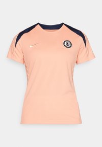 Maillot de sport pêche avec des manches courtes, accents navy sur les épaules, logo doré de Nike, et emblème du club Chelsea FC sur la poitrine.