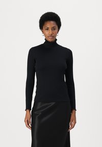 Black turtleneck long-sleeve top in smooth fabric, featuring a fitted design and subtle ruffle at the neck. Paired with a black satin skirt.
