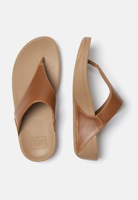Brune lærflip-flops med en tærsko med en thong-rem og tekstureret tan sål. Har et buet design og en karakteristisk lagdelt detalje på siderne.