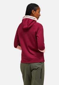 Bordeauxkleurige hoodie met een contrasterende roze kraag, voorzien van een logo op de achterkant. Glad stof; lange mouwen met roze accenten.