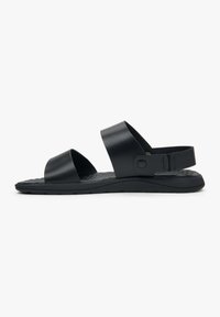 Czarne sandały z dwoma szerokimi paskami, wyściełanym wkładkiem i teksturowaną podeszwą. Posiadają regulowany pasek na kostkę z zapięciem na zatrzask.