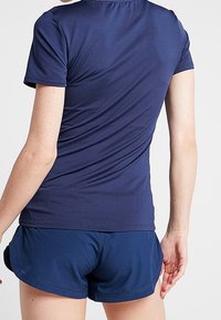 Camisa atlética de color azul marino con mangas cortas, que presenta una textura suave. Combinada con pantalones cortos a juego en azul marino, que ofrecen un ajuste cómodo.