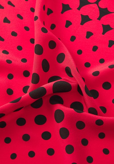 Tecido vermelho com uma textura suave, apresentando grandes bolinhas pretas e pequenos desenhos em forma de estrela, dispostos em um padrão dinâmico.