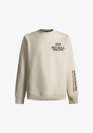 Sudadera color crema con cuello redondo acanalado. Presenta el texto "RED BULL RACING" y "Equipamiento de Carreras Auténtico" impreso en negro y rojo.