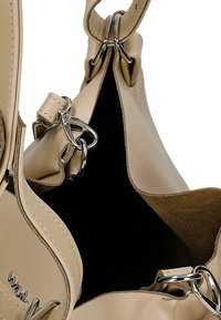 Borsa a mano in pelle beige con un'esterno liscio, hardware argentato e un interno morbido e scuro. Presenta un'apertura spaziosa e una particolare dettaglio di cucitura.