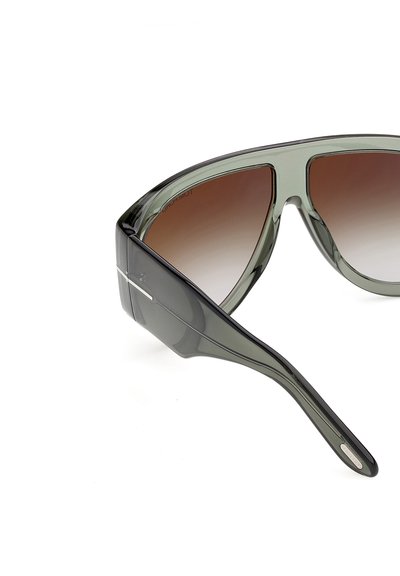 Lunettes de soleil translucides grises oversize avec verres dégradés marron et branches épaisses larges présentées sur un fond blanc.