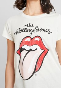 Bílá bavlněná trička s velkým červeným a černým grafikou loga Rolling Stones se designem jazyka, krátkými rukávy a kulatým výstřihem.