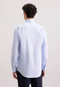 Camicia a maniche lunghe azzurro chiaro realizzata in tessuto testurizzato, con colletto a punta, polsini con bottoni e orlo curvo. Dettagli di design sottili evidenti.