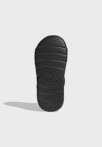 Sort slide sandal med en tekstureret gummis�ål med dybe riller og et prægede logo. Rundet form med design med åben ryg.